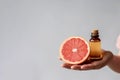 Essential Oil Of Grapefruit In Small Brown Bottle With Grapefruit In Womens Hands On White Background. Generative AI