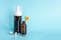 Essential oil in open brown dropper bottle with lying glass pipette, big bottle with white dispenser and orange flower calendula Royalty Free Stock Photo