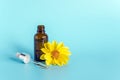 Essential oil in open brown dropper bottle with lying glass pipette and yellow flower on blue background. Concept natural organic Royalty Free Stock Photo