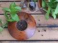 Essential oil in bottle and fresh leaf of mint with pepper in bowl