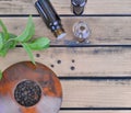 Essential oil bottle and fresh eaf of mint with pepper seed in bowl on wooden background