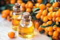 Essential oil of sea buckthorn Hippophae in glass bottle with fresh, juicy ripe yellow berries on the branch with green leaves-b