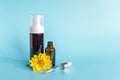 Essential oil in small open brown dropper bottle with lying glass pipette, big bottle with white dispenser and yellow flower on Royalty Free Stock Photo