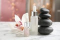 Essential oil, spa stones and orchid flower on white marble table against blurred lights Royalty Free Stock Photo