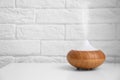 Essential oils diffuser on white table   near  wall. Space for text Royalty Free Stock Photo