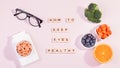 Essential vitamins and supplements to keep eyes healthy on pink background. Eyeglasses, vitamin pills, food containing vitamins