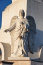 Statue of an angel holding a candlestick in a sculptural composition at the foot of the statue of Christ