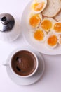 Esspresso coffee and soft boiled egg halves on the white plate and bread slices Royalty Free Stock Photo