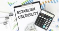Establish credibility. text on notepad pages on white paper on light background near calculator Royalty Free Stock Photo