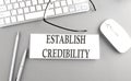ESTABLISH CREDIBILITY text on paper with keyboard on grey background Royalty Free Stock Photo