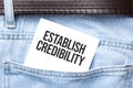 ESTABLISH CREDIBILITY words on a white paper stuck out from jeans pocket. Business concept