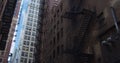 Establishing shot apartment building during the day. Windows and steel fire escape hub the brick facade for safety.