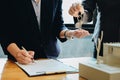 Estate agent giving house keys to woman and sign agreement in office Royalty Free Stock Photo