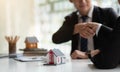 Estate agent shaking hands with his customer after contract signature, Contract document and house model on wooden desk Royalty Free Stock Photo