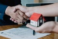 Estate agent shaking hands with his customer hand holding house Royalty Free Stock Photo