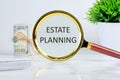 Estate Planning text writing through a magnifying glass on a light background near a roll of money and a pot of green grass Royalty Free Stock Photo