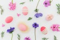 Ester holiday composition with colorful eggs, spring flowers, hypericum and leaves of lavender on white. Flat lay