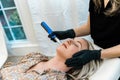 An esthtetician microneedling a spa client as she lies on a table in a health and wellness medical clinic