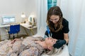 An esthtetician microneedling a spa client as she lies on a table in a health and wellness medical clinic