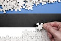 Estonia flag is depicted on a table on which the human hand folds a puzzle of white color Royalty Free Stock Photo