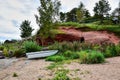 A red sandstone hill covered with green grass and trees