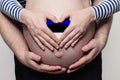 Estonian family concept. Man embracing pregnant woman belly and heart with flag of Estonia colors closeup Royalty Free Stock Photo