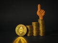 An ethereum coin, stacks of coins and a figure of a hand with a finger up on a black background. The concept of the rise in the