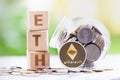 Ethereum ETH Coins and Wood block word ETH on blurred greenery background.