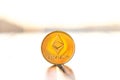Ethereum gold color coin with sunset white background. Cryptocurrency virtual coin.