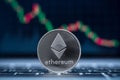 Ethereum physical coin symbol on laptop with downtrend price graph background