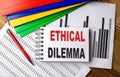 ETHICAL DILEMMA text on notebook with pen, folder on a chart background