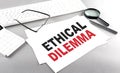 ETHICAL DILEMMA text on a paper on a gray background near a calculator and a white keyboard