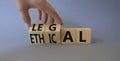 Ethical and Legal symbol. Businessman hand turnes wooden cubes and changes word Ethical to Legal. Beautiful grey background. Royalty Free Stock Photo