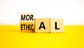 Ethical or moral symbol. Businessman turns wooden cubes and changes the word Ethical to Moral on a Beautiful yellow table white Royalty Free Stock Photo