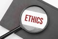 Ethics word on paper through magnifying lens