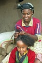 Ethiopian teenager braid her sisters hair