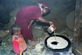 Ethiopian woman with son bakes injera on wood fire