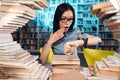 Ethnic asian girl surrounded by books in library at night. Student is looking at watch. Royalty Free Stock Photo