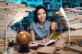 Ethnic asian girl surrounded by books in library. Student is writing in notebook. Royalty Free Stock Photo