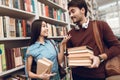Ethnic asian girl and white guy in library. Students are looking for books. Royalty Free Stock Photo