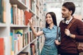 Ethnic asian girl and white guy in library. Students are looking for books.