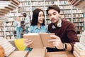 Ethnic asian girl and white guy surrounded by books in library. Students are reading book. Royalty Free Stock Photo