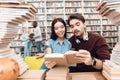 Ethnic asian girl and white guy surrounded by books in library. Students are reading book. Royalty Free Stock Photo