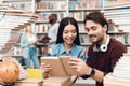 Ethnic asian girl and white guy surrounded by books in library. Students are reading book. Royalty Free Stock Photo