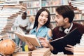 Ethnic asian girl and white guy surrounded by books in library. Students are reading books. Royalty Free Stock Photo