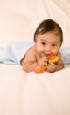 Ethnic baby boy with toy lying down on blanket