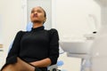 Ethnic black female patient sitting looking up on dental chair waiting for her dentist