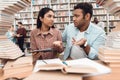 Ethnic indian mixed race girl and guy surrounded by books in library. Students are taking notes. Royalty Free Stock Photo