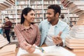 Ethnic indian mixed race girl and guy surrounded by books in library. Students are taking notes. Royalty Free Stock Photo