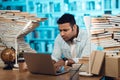 Ethnic indian mixed race guy surrounded by books in library. Student is using laptop. Royalty Free Stock Photo